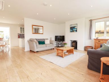 A living room with a sofa, coffee table, and television at Cloudbreak in Wadebridge