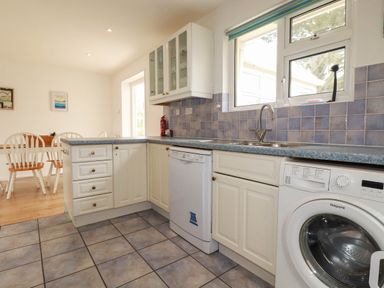 A kitchen with a sink, dishwasher, and washing machine at Cloudbreak in Wadebridge