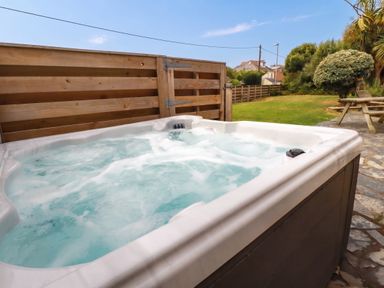 A hot tub in a garden area at Cloudbreak Wadebridge