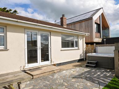An outdoor area with a house, hot tub, and stone patio at Cloudbreak in Polzeath