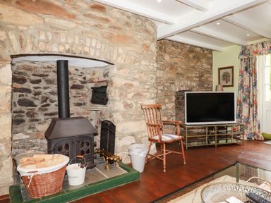 A living room with a wooden stove and television at The Homestead in 