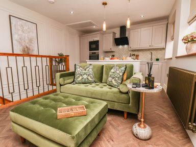 A living room with a green sofa and coffee table at 14 Brunswick Street Whitby