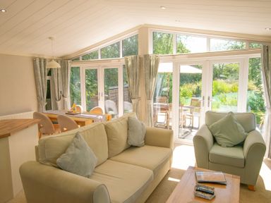A living room with a sofa and dining area at Ash Lodge in Stowmarket