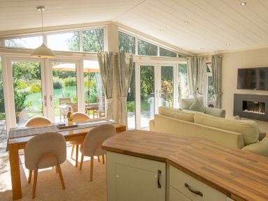 A living room with a dining table and sliding doors at Ash Lodge in Stowmarket