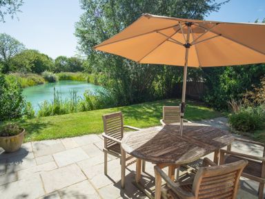 A garden with a table and chairs near a pond at Ash Lodge in Stowmarket
