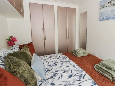 A bedroom with a bed and wardrobe at 73 Cildraeth New Quay