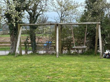 A swing set in a yard with grass and trees at the property