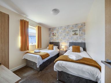 A bedroom with twin beds and a nightstand at Seaside Chalet Retreat in Bridlington