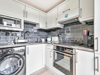 A kitchen with appliances and a washing machine at Torpoint Apartment Sleeps4 Seaside Parking Downderry