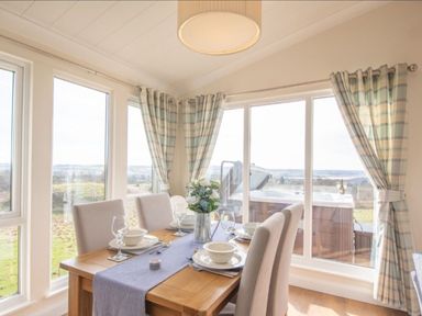 A dining room with a table set for dinner at 2 Bedroom Sleeps 4 Lodge Smart Tv Hot tub Dogs Ok near Lochwinnoch