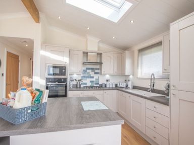 A kitchen with appliances and a basket of groceries at 2 Bedroom Sleeps 4 Lodge Smart Tv Hot tub Dogs Ok near Lochwinnoch