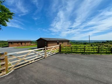 An exterior view of lodges with a gate at 2 Bedroom Sleeps 4 Lodge Smart Tv Hot tub Dogs Ok near Lochwinnoch