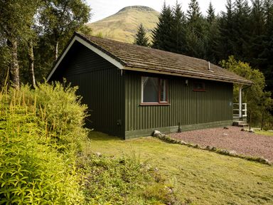An outdoor view of a lodge surrounded by greenery at 2 bedroom lodge with free WiFi and mountain view near Crianlarich
