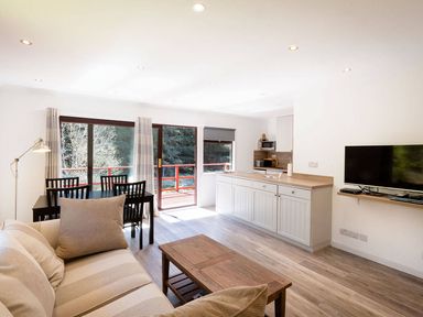 A living room with a kitchen area and dining table at 2 bedroom lodge with free WiFi and mountain view near Crianlarich