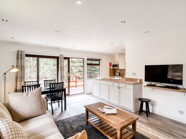 A living room with a dining area and kitchen at 2 bedroom lodge with free WiFi and mountain view near Crianlarich