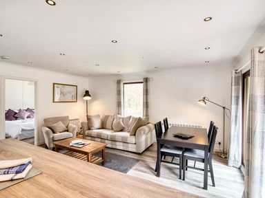 A living room with a sofa and dining area at 2 bedroom lodge with free WiFi and mountain view near Crianlarich