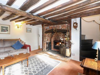 A living room with a fireplace and sofa at Hollyhedge Cottage in Briston