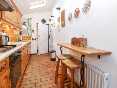 A kitchen with wooden cabinets and a table in Hollyhedge Cottage Briston