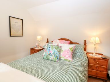A bedroom with a bed, pillows, and a lamp at Hollyhedge Cottage, Briston