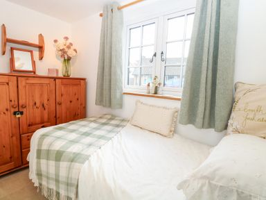 A bedroom with a bed and a cabinet at Hollyhedge Cottage in Briston