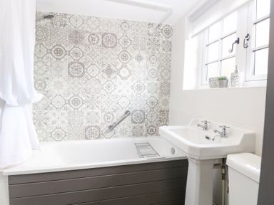 A bathroom with a bathtub and washbasin at Hollyhedge Cottage in Briston