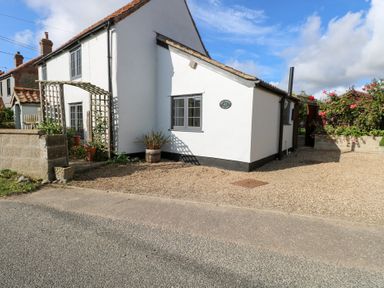 A house with windows and gravel in front at Hollyhedge Cottage in Briston