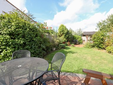 A garden with a table and chairs at Hollyhedge Cottage in Briston
