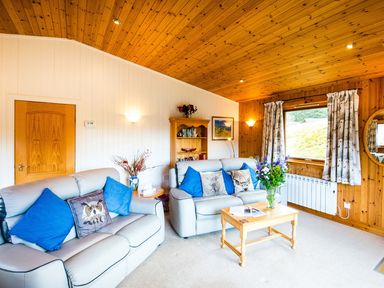 A living room with sofas and a coffee table at Raven Lodge with beautiful views of Loch Dochart near Crianlarich