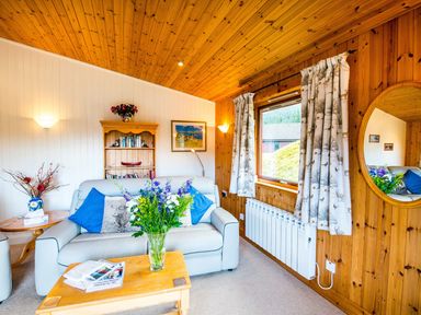 A living room with a sofa and a coffee table at Raven Lodge with beautiful views of Loch Dochart near Crianlarich