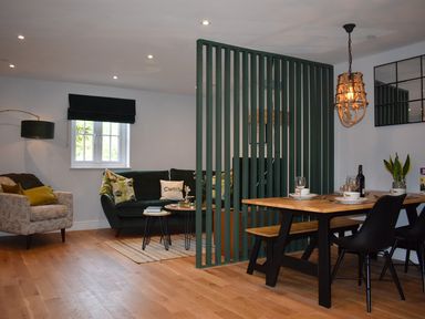 A living room with a sofa and dining area at Yr Hen Beudy Barn Conversion Sleeps 4 Dogs Ok near Brodle Farm near Llansteffan
