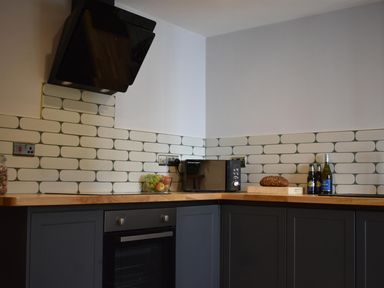 A kitchen with an oven and microwave at Yr Hen Beudy Barn Conversion Sleeps 4 Dogs Ok, Brodle Farm near Llansteffan