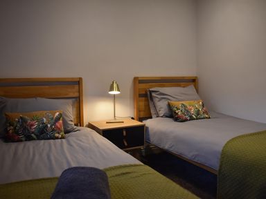 A bedroom with two beds and a lamp at Yr Hen Beudy Barn Conversion Sleeps 4 Dogs Ok near Brodle Farm near Llansteffan