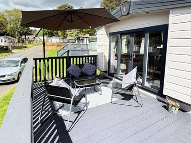 An outdoor area with chairs and an umbrella at Lillardsedge Luxury Caravan Sleeps 6 with Parking Lilliardsedge Holiday Park near St Boswells