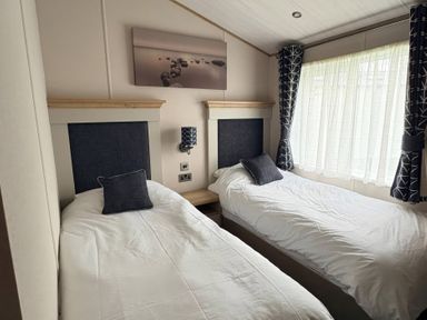 A bedroom with two single beds and a window at Harrogate Lodge Sleeps4 South Facing Decking Lufflands Caravan Park near Holsworthy
