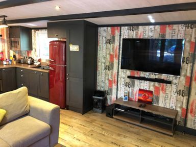A kitchen with a red refrigerator and a television at Sandy Balls Holiday Park Pet Friendly Lodge, Godshill, Hampshire