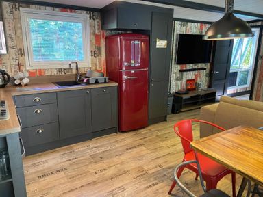A kitchen with a refrigerator and a dining table at Sandy Balls Holiday Park Pet Friendly Lodge in Godshill, Hampshire