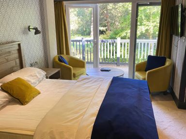 A bedroom with a bed and chairs at Sandy Balls Holiday Park Pet Friendly Lodge in Godshill, Hampshire