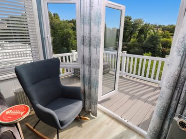 A conservatory with a rocking chair and open window at Pleasant Valley Holiday Lodge 70 in Stepaside