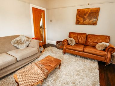 A living room with a sofa and footstool at 11 Bryn Goleu Avenue North Holyhead
