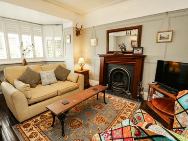 A living room with a sofa, fireplace and television at 11 Bryn Goleu Avenue North in Holyhead