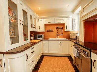 A kitchen with cabinets, sink, oven and microwave at 11 Bryn Goleu Avenue North in Holyhead