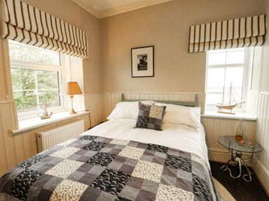 A bedroom with a bed, lamp, and window at 11 Bryn Goleu Avenue North in Holyhead