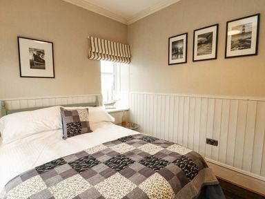 A bedroom with a bed and photographs on the wall at 11 Bryn Goleu Avenue North Holyhead