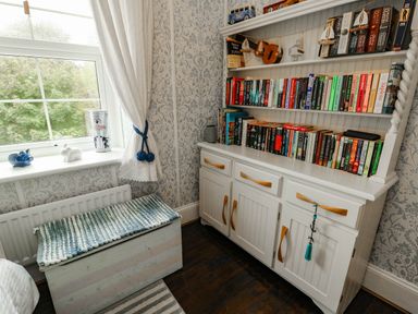 A bedroom with a bookshelf and storage bench at 11 Bryn Goleu Avenue North Holyhead