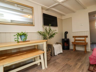 A snug with a table, chair, plant, fireplace, and television at Blue Cottage in Malton