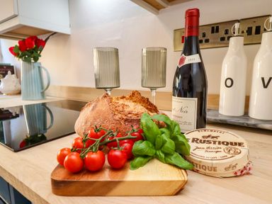 A kitchen with tomatoes, bread, wine, and cheese at Blue Cottage in Malton