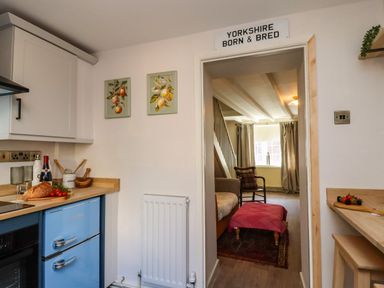 A kitchen with a doorway leading to a living area at Blue Cottage in Malton