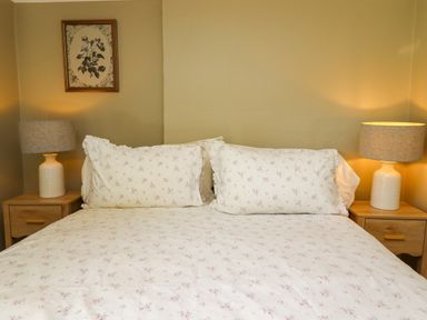 A bedroom with a bed and nightstands at Blue Cottage in Malton