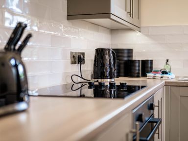 A kitchen countertop with a kettle and cooking hob at Bay Bungalow