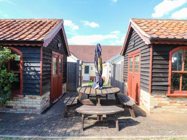 A picnic table with chairs and umbrella between two wooden buildings at The Mill House Apartment